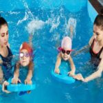 Two women & two kids in goggles splash in a pool, showing swim do’s and don’ts in San Francisco, CA.